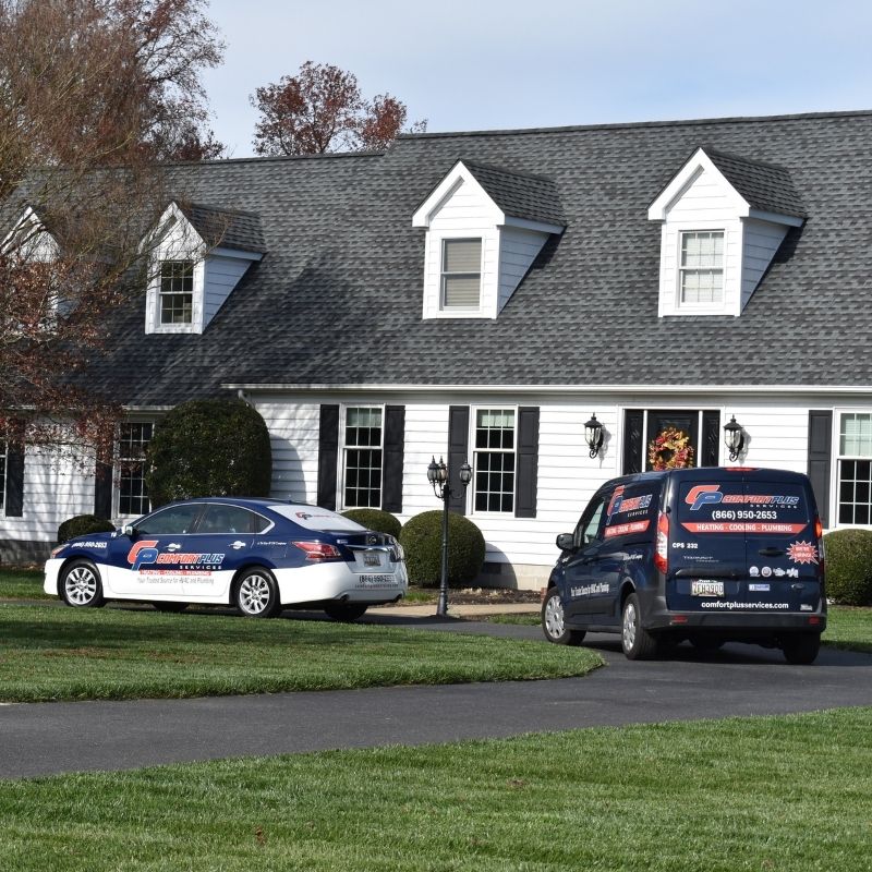 The Comfort Plus Services HVAC service van and a technician's CPS car in front of a home in Seaford, DE.