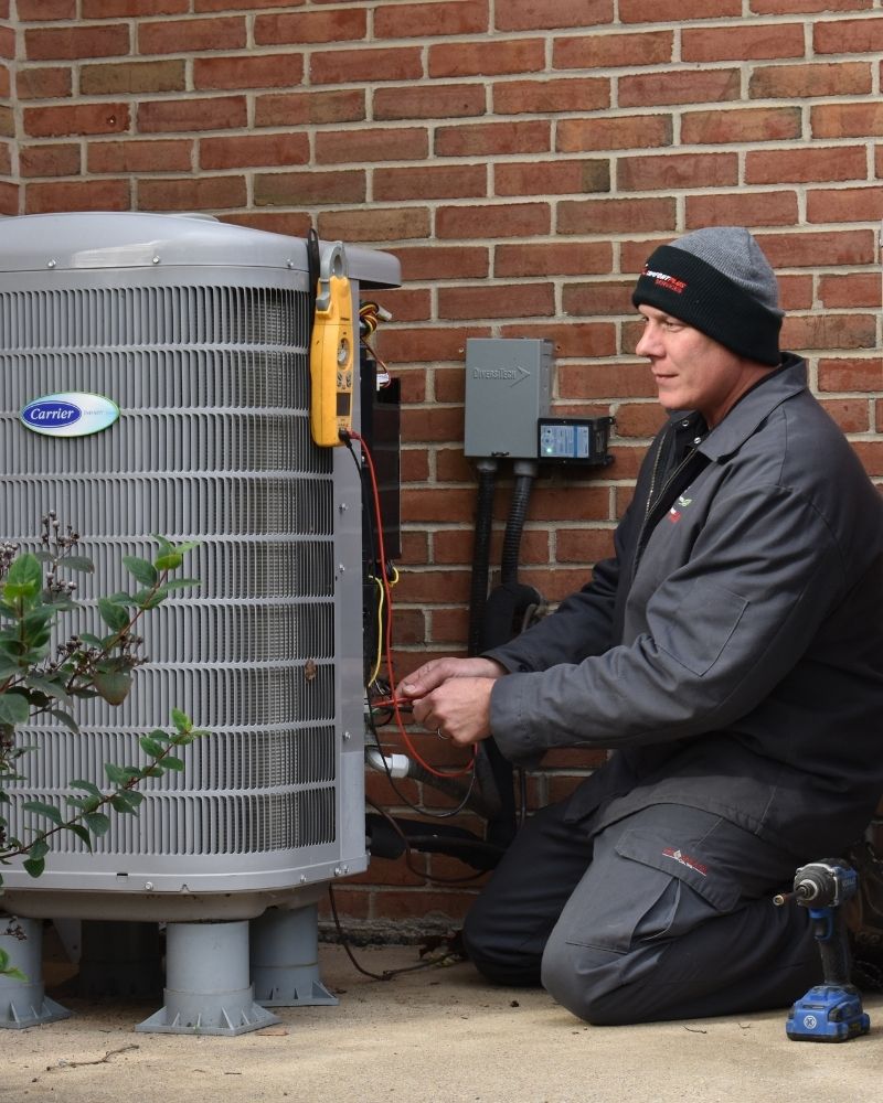 CPS working on hvac unit outside A Comfort Plus Services HVAC technician performs electrical continuity and function tests on an outdoor Carrier HVAC condenser unit in Sussex County.