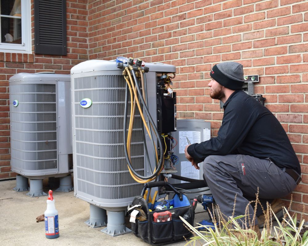 A NATE-certified Comfort Plus Services HVAC technician services a Carrier condenser unit at a home in Delaware.