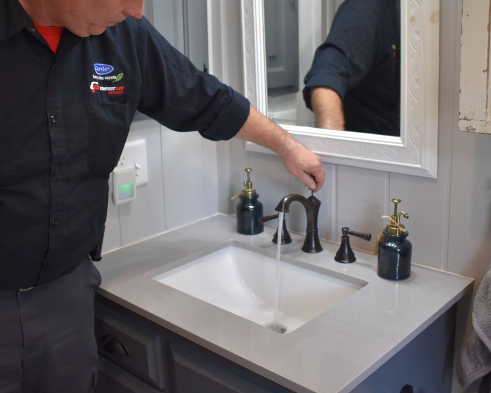plumber checking faucet stopper A Comfort Plus Services plumber tests a new bathroom sink faucet stopper after a new installation.