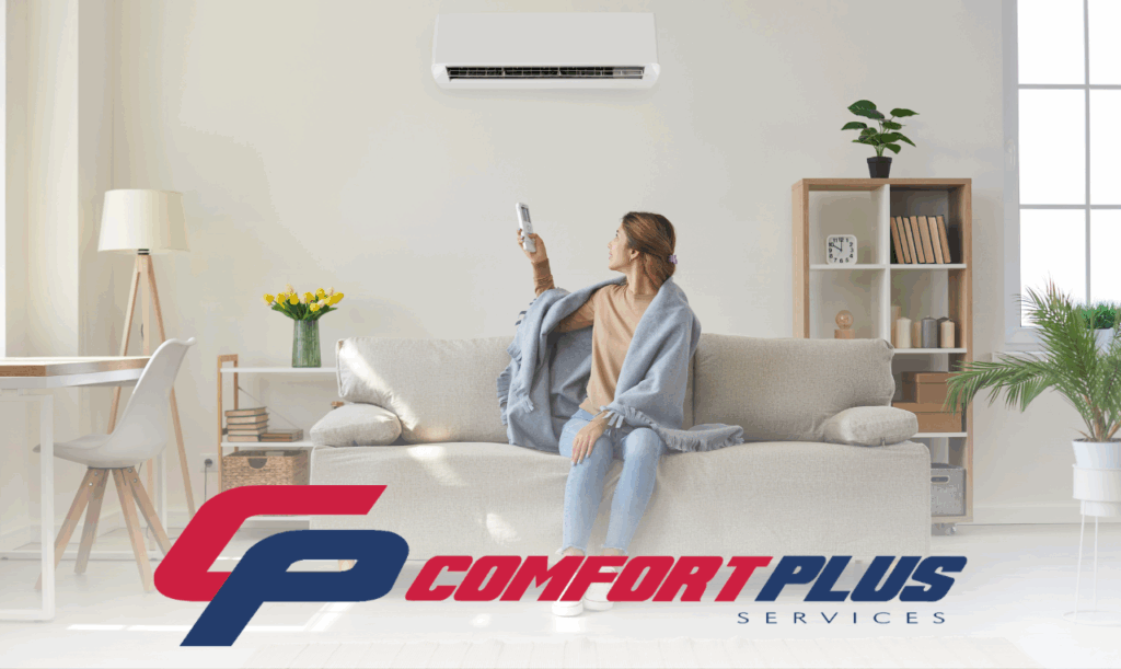 A woman adjusts the temperature of a ductless mini-split HVAC system in her living room, while wrapped in a blanket.