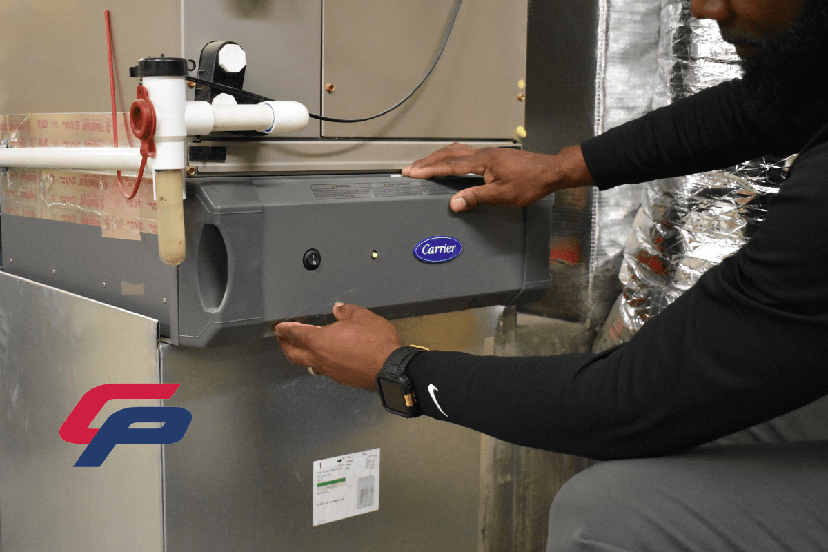 Close up of heating system maintenance, featuring a Comfort Plus Service technician servicing a Carrier brand indoor air handler.